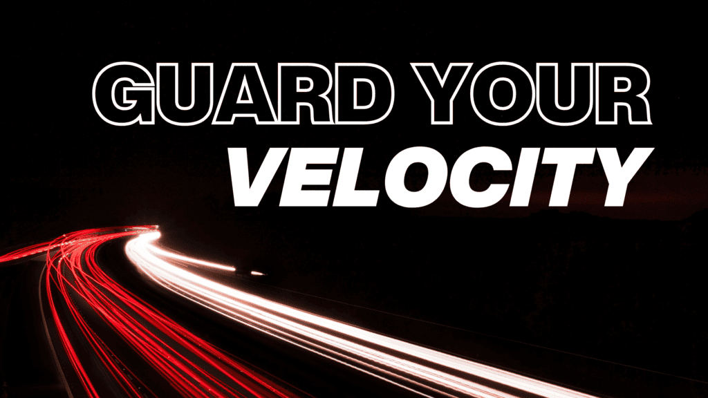 A highway at night with red and white light trails in motion, with the words ‘Guard Your Velocity’ reminding viewers to maintain focus and forward movement.