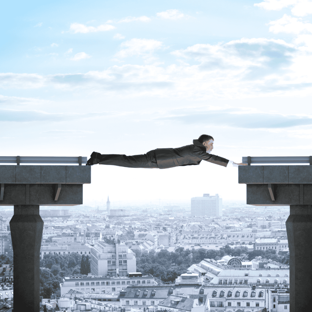 A businessman in a suit stretches across a gap between two unfinished bridge sections high above a cityscape, symbolizing the consequences of prioritizing efficiency over stability and long-term planning.