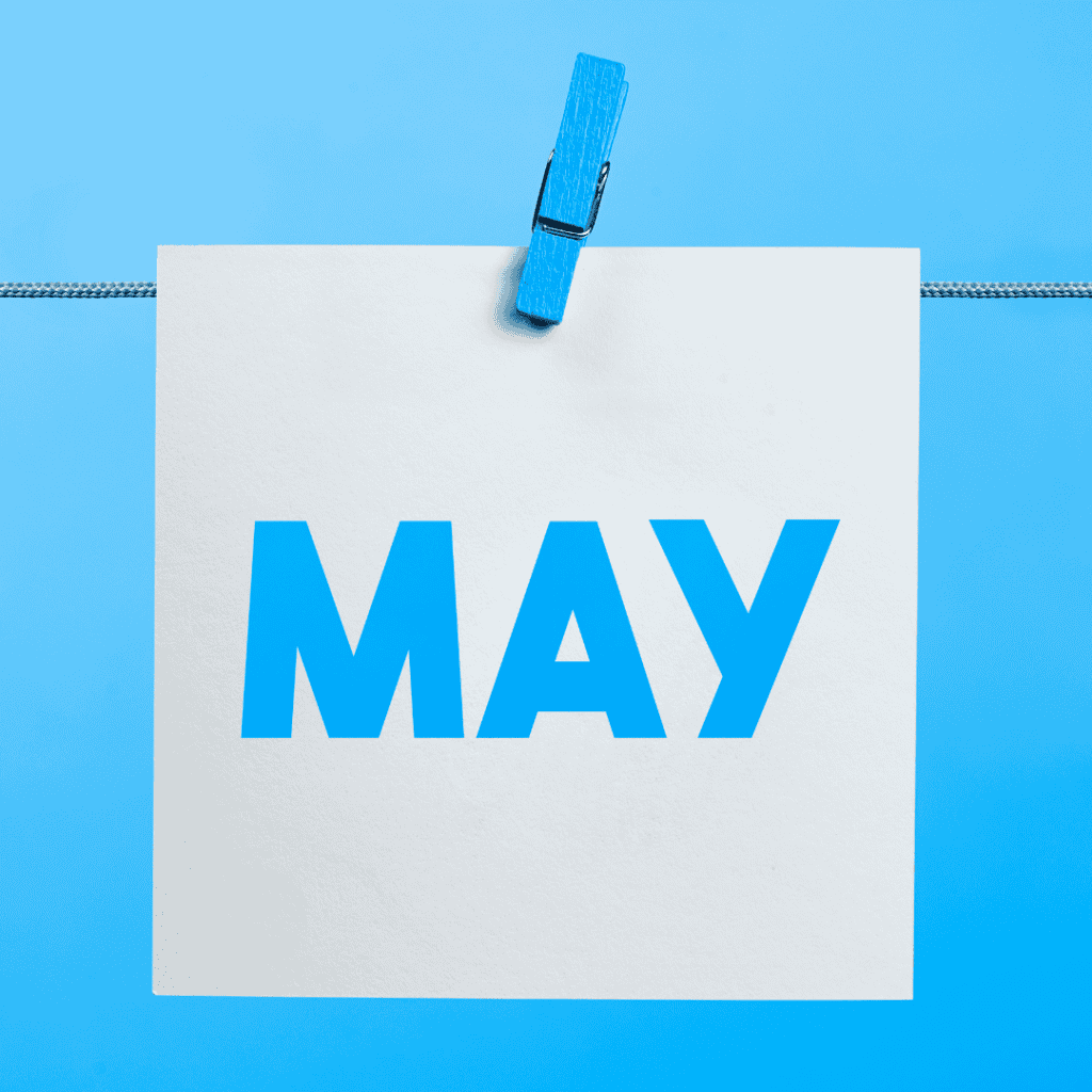 The word "May" on a square piece of paper hanging from a clothesline by a blue clothespin.