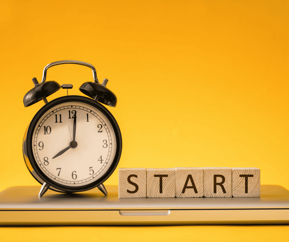 An analog alarm clock with bells on it placed next to Scrabble tiles that spell START.