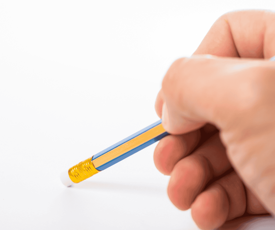 Close-up of a hand using a pencil eraser to remove marks from a blank surface, symbolizing the intentional removal of unnecessary work