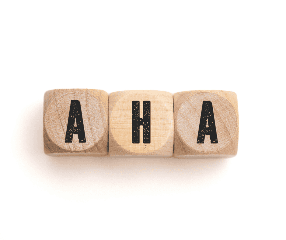 Three wooden blocks spelling AHA to highlight the aha moment verus the post highlighting the difference between an AHA and an epiphany.