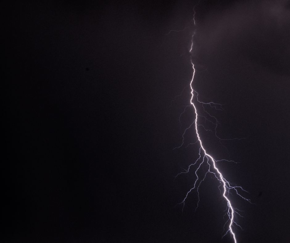 A single bolt of lightning branching against a black night sky, representing the sudden jolt behind why we quit our jobs